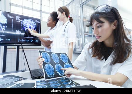 giovane femmina studente dottore internship gruppo di riunione e di discussione sul cancro al cervello chirurgia trattamento caso paziente presso l'ufficio di laboratorio a hospit Foto Stock