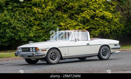 Whittlebury, Northants, Regno Unito - 27 agosto 2023: 1976 auto bianca Triumph Stag che viaggia su una strada di campagna inglese Foto Stock