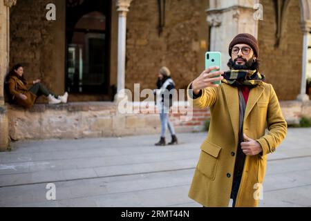 happy bearded young man taking a selfie in the old city - Young man using mobile phone at historic building. Vacations concept Foto Stock