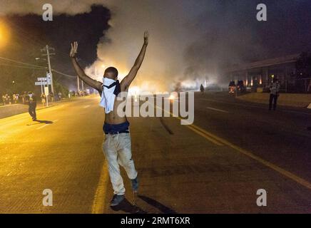 140819 -- FERGUSON, 19 agosto 2014 -- un manifestante si allontana con le mani alzate dal fumo di gas lacrimogeni durante le proteste contro l'uccisione di Michael Brown da parte della polizia a Ferguson, Missouri, Stati Uniti. il diciottenne afro-americano Michael Brown è stato ucciso dalla polizia a Ferguson, scatenando continue proteste nella città dove la maggior parte della popolazione è nera. US-MISSOURI-FERGUSON-PROTESTA-SCONTRO ShenxTing PUBLICATIONxNOTxINxCHN Foto Stock