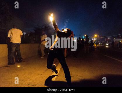 (140819) -- FERGUSON, 19 agosto 2014 -- un manifestante rilancia un contenitore di gas lacrimogeni sparato dalla polizia durante le proteste contro l'uccisione di Michael Brown da parte della polizia a Ferguson, Missouri, Stati Uniti.il diciottenne afro-americano Michael Brown è stato ucciso dalla polizia a Ferguson, scatenando continue proteste nella città dove la maggior parte della popolazione è nera. ) US-MISSOURI-FERGUSON-PROTESTA-CLASH ShenxTing PUBLICATIONxNOTxINxCHN Ferguson 19 agosto 2014 un manifestante getta indietro un contenitore SPARATO dalla polizia durante la protesta contro l'uccisione di Michael Brown da parte della polizia a Ferguson, Missouri, Stati Uniti Foto Stock