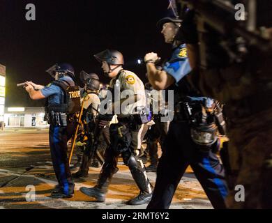 (140819) -- FERGUSON, 19 agosto 2014 -- i poliziotti tengono le armi e iniziano a liberare la zona durante le proteste contro l'uccisione di Michael Brown da parte della polizia a Ferguson, Missouri, Stati Uniti. il diciottenne afro-americano Michael Brown fu ucciso dalla polizia a Ferguson, scatenando continue proteste nella città dove la maggior parte della popolazione è nera. US-MISSOURI-FERGUSON-PROTESTA-CLASH ShenxTing PUBLICATIONxNOTxINxCHN Ferguson 19 agosto 2014 i poliziotti tengono le armi e iniziano a sgomberare l'area durante la protesta contro l'uccisione di Michael Brown da parte della polizia a Ferguson Missouri Stati Uniti 1 Foto Stock