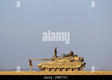 (140819) -- FRONTIERA DI GAZA, 19 agosto 2014 -- soldati israeliani sono visti accanto a un carro armato Merkava in un'area di sosta nel sud di Israele al confine con la Striscia di Gaza, il 19 agosto 2014. Tre palestinesi sono stati uccisi e altri 40 feriti negli intensivi attacchi aerei israeliani sulla città di Gaza martedì sera, poco prima della fine di un cessate il fuoco di 24 ore nella Striscia di Gaza, hanno detto i medici. JINI/) ISRAEL-GAZA-CESSATE IL FUOCO-END IlanxAsayaag PUBLICATIONxNOTxINxCHN frontiera di Gaza 19 agosto 2014 soldati israeliani sono laghi accanto a un carro armato Merkava IN una zona di sosta nel sud di Israele borde ring the Gaza Strip IL 19 agosto 2014 tre Foto Stock