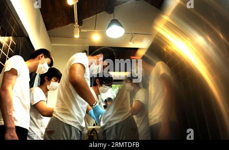 Chen Jingchao (1st R) e i suoi apprendisti fanno caramelle a Yoo Candy a Pechino, capitale della Cina, 29 agosto 2014. Come chef di caramelle di Yoo Candy, un negozio di dolciumi a Nanluoguxiang di Pechino, il compito di Chen Jingchao è produrre dolci freschi fatti a mano insieme ai suoi apprendisti. Precedentemente professionista IT a Shanghai, il giovane di 24 anni ha iniziato a imparare la produzione di candele nel 2013 e ha deciso di proseguire la sua carriera a Pechino lo scorso maggio. Il prodotto di successo di Yoo Candy è il rock australiano , una caramella cilindrica dura con disegno a motivi sulle due estremità. Chen può creare circa 50 modelli sul Foto Stock