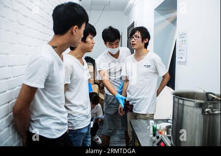 Chen Jingchao (1st R) e i suoi tre apprendisti bollono lo sciroppo di zucchero di malto a Pechino, capitale della Cina, 29 agosto 2014. Come chef di caramelle di Yoo Candy, un negozio di dolciumi a Nanluoguxiang di Pechino, il compito di Chen Jingchao è produrre dolci freschi fatti a mano insieme ai suoi apprendisti. Precedentemente professionista IT a Shanghai, il giovane di 24 anni ha iniziato a imparare la produzione di candele nel 2013 e ha deciso di proseguire la sua carriera a Pechino lo scorso maggio. Il prodotto di successo di Yoo Candy è il rock australiano , una caramella cilindrica dura con disegno a motivi sulle due estremità. Chen può creare circa 50 schemi su t Foto Stock