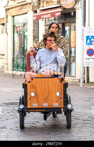 Madre e bambino parzialmente disabile in sella a una bici elettrica Eco-Triporteur assistita cargo - Tours, Indre-et-Loire (37), Francia. Foto Stock