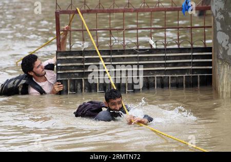 (140912) -- SRINAGAR, 12 settembre 2014 -- i volontari si sono tuffati nelle acque alluvionali per distribuire aiuti alle persone colpite dalle inondazioni a Srinagar, capitale estiva del Kashmir controllato dagli indiani, 12 settembre 2014. Srinagar è stata colpita da una devastante inondazione flash da sabato sera a domenica mattina, con la maggior parte della città sott'acqua. Decine di migliaia sono rimaste intrappolate nella città di Srinagar e il numero esatto di vittime non può essere fatto finché l'esercito e i soccorritori non raggiungono tutte le aree sommerse. )(cy) KASHMIR-SRINAGAR-FLOOD JavedxDar PUBLICATIONxNOTxINxCHN Srinagar 12 settembre 2014 volontari di vitello nelle acque alluvionali t Foto Stock