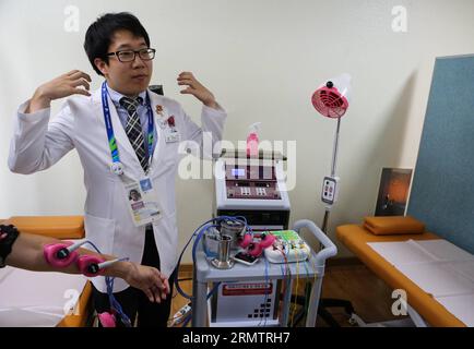 (140917) -- INCHEON, 17 settembre 2014 -- Un medico dimostra l'agopuntura elettronica nel villaggio degli atleti di Incheon, Corea del Sud, 17 settembre 2014. L'Athletes Village si trova a 10 chilometri dal Main Press Center. Si compone di 22 condomini che forniscono un totale di 2.200 camere. I diciassettesimi Giochi asiatici si terranno dal 19 settembre al 4 ottobre. )(lz) (SP)COREA DEL SUD-INCHEON-ASIAN GAMES-ATHLETES VILLAGE Zhangxfan PUBLICATIONxNOTxINxCHN Incheon 17 settembre 2014 un Dottore dimostra l'agopuntura elettronica nel Villaggio degli atleti di Incheon Corea del Sud 17 settembre 2014 The Athletes Foto Stock