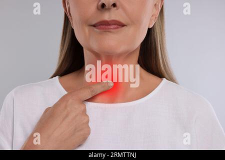 Sistema endocrino. Donna che fa l'autoesame della tiroide su sfondo grigio chiaro, primo piano Foto Stock