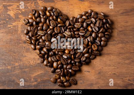 chicchi di caffè biologici disposti a forma di cuore sul vecchio tavolo di legno Foto Stock