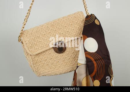 Borsa di colore beige chiaro a uncinetto con scialle marrone isolato su sfondo bianco. Foto Stock