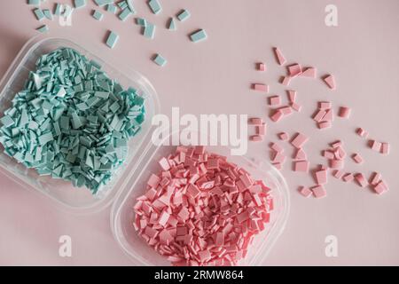 Una pila di plastica - piccoli pezzi di plastica dura, di colore rosa e blu, destinati a ulteriori lavorazioni Foto Stock