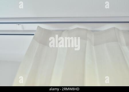 Tenda testurizzata bianca traslucida sulla finestra, primo piano della cornice e tessuto raccolto sulla treccia Foto Stock