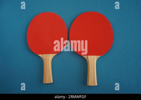 Due racchette da ping pong o da ping pong rosse si trovano su uno sfondo blu con vista ravvicinata dall'alto. Gioco per il tempo libero. Attrezzature sportive. Internazionale Foto Stock