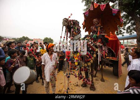 (141031) -- RAJASTHAN, 31 ottobre 2014 -- l'artista Ashok Tak siede su un carretto di cammelli decorato da lui stesso durante uno spettacolo di decorazione di cammelli alla Camel Fair di Pushkar del Rajasthan, India, il 31 ottobre 2014. Migliaia di commercianti di bestiame vengono alla tradizionale fiera annuale dei cammelli, dove vengono commerciati bestiame, principalmente cammelli. Questa fiera è una delle più grandi fiere mondiali di cammelli. INDIA-RAJASTHAN-PUSHKAR-CAMEL FAIR ZhengxHuansong PUBLICATIONxNOTxINxCHN Rajasthan OCT 31 2014 l'artista Ashok Tak siede SU un cammello decorato da lui stesso durante uno spettacolo di decorazione del cammello ALLA Fiera del cammello a Pushkar del Rajasthan I. Foto Stock