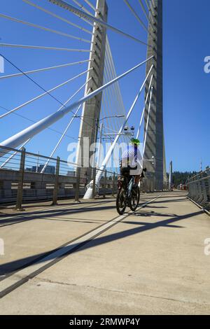 Uomo in bicicletta attraverso il fiume Willamette sul Tillicum Crossing/Bridge of the Gods nel centro di Portland, Oregon Foto Stock