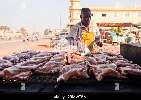 (141110) - OUAGADOUGOU, 10 novembre 2014. -- Un falco cuoce le zampe di montone arrosto a Ouagadougou, capitale del Burkina Faso, 10 novembre 2014. ) BURKINA FASO-OUAGADOUGOU-STREET VIEW LixJing PUBLICATIONxNOTxINxCHN Ouagadougou Nov 10 2014 a Hawker Cooks Roasted Mutton Legs in Ouagadougou capitale del Burkina Faso Nov 10 2014 Burkina Faso Ouagadougou Street View PUBLICATIONTxINxCHN Foto Stock