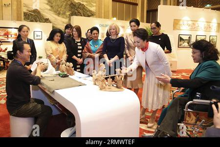 (141110) -- PECHINO, 10 novembre 2014 -- Peng Liyuan (in abito bianco), moglie del presidente cinese Xi Jinping, vede la ceramica creata dall'artista sordomuto Kang Zhimin insieme ai coniugi di alcuni leader delle economie membri della cooperazione economica Asia-Pacifico (APEC) durante un'attività incentrata sulle questioni di sviluppo riguardanti i disabili, a Pechino, in Cina, 10 novembre 2014. )(hdt) (APEC 2014) CHINA-BEIJING-APEC-PENG LIYUAN-SPOSES-ACTIVITY (CN) HuangxJingwen PUBLICATIONxNOTxINxCHN Pechino Nov 10 2014 Peng Liyuan in abito bianco moglie del presidente cinese Xi Jinping vede la ceramica creata Foto Stock