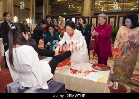 (141110) -- PECHINO, 10 novembre 2014 -- Peng Liyuan (terza R, fronte), moglie del presidente cinese Xi Jinping, riceve un lavoro di taglio delle carte creato da Xia Hong, una giovane donna che ha perso le braccia, in regalo, mentre partecipa a un'attività incentrata sulle questioni di sviluppo riguardanti i disabili insieme ai coniugi di alcuni leader delle economie membri della cooperazione economica Asia-Pacifico (APEC) a Pechino, in Cina, 10 novembre 2014. )(lmm) (APEC 2014) CHINA-BEIJING-APEC-PENG LIYUAN-SPOSES-ACTIVITY (CN) HuangxJingwen PUBLICATIONxNOTxINxCHN Beijing Nov 10 2014 Peng Liyuan 3rd r Front wife of Chinese Presiden Foto Stock