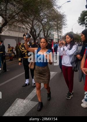 Lima, Peru - July 29 2023: Peruvian Woman Taking Pictures with her Cell Phone at the Independence Day Military Parade Stock Photo