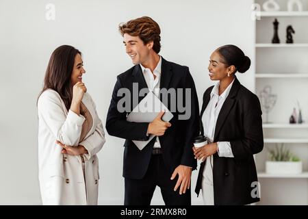 Tre colleghi d'affari multirazziali che parlano mentre fanno una pausa in ufficio all'interno Foto Stock