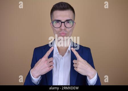 Troppo sicuro Young bell'uomo elegante che punta su se stesso su uno sfondo isolato Foto Stock