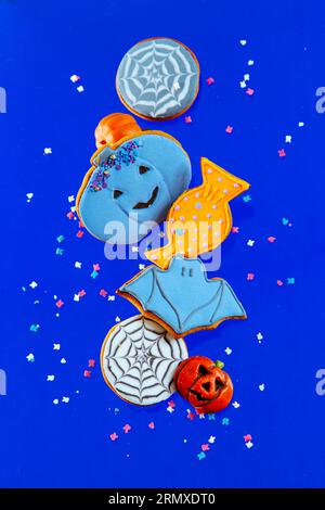 Biscotti di pan di zenzero dipinti di Halloween con spruzzate su sfondo blu. Levitazione. Foto Stock