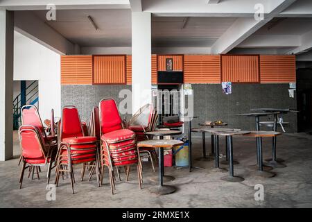 Posti a sedere e tavoli accumulati in un ristorante vuoto su Walking St Pattaya, Thailandia. Foto Stock