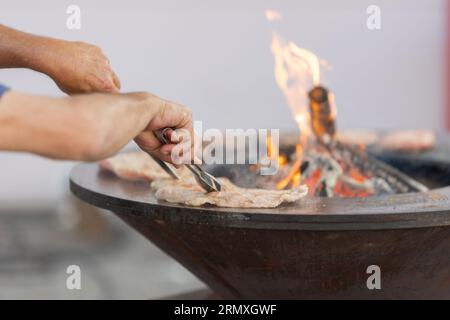 Lo chef cuoce la carne sul fornello con un fuoco. Scatto medio Foto Stock