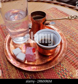 Caffè bosniaco con cubetti di zucchero, Turkish Delight , servito su un vassoio di rame e utensili e un bicchiere d'acqua nella città di Sarajevo, 30 agosto 2023 Foto Stock