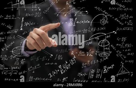 Side portrait of handsome young businessman writing mathematical formulas on bright city background Foto Stock