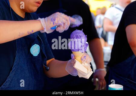 Un lavoratore con scarpetta morbida raccoglie una doppia paletta di gelato su un cono di cialda in una fiera di strada del Philippines Fest a New York, il 27 agosto 2023. Foto Stock