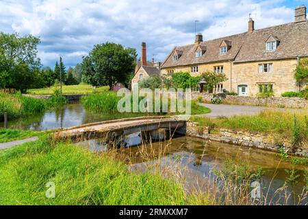 A small pedestrian bridge over the River Eye at the idyllic Cotswold village of Lower Slaughter, England UK. Stock Photo