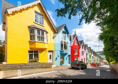 Il pittoresco e colorato Deck of Cards, una fila di case cittadine dipinte con colori vivaci, viste dal parco Garden of Reflection di Cobh, Irlanda. Foto Stock