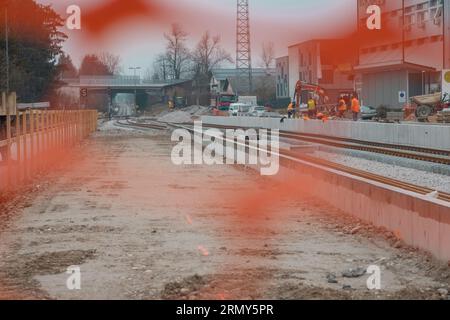 Modernizzazione della vecchia stazione ferroviaria di Domzale, città periferica di lubiana. Lavoratori che posano nuovi cingoli con ghiaia e nuova piattaforma pedonale. A guardare Foto Stock