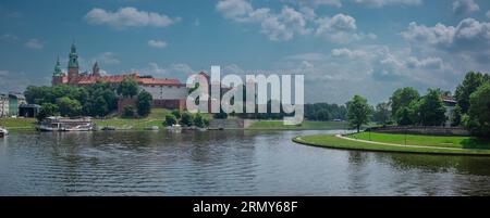 Ampio panorama del castello di Wawel con vista sul fiume Wisla in una soleggiata giornata estiva. Barche fluviali e cieli soffici visibili. Foto Stock