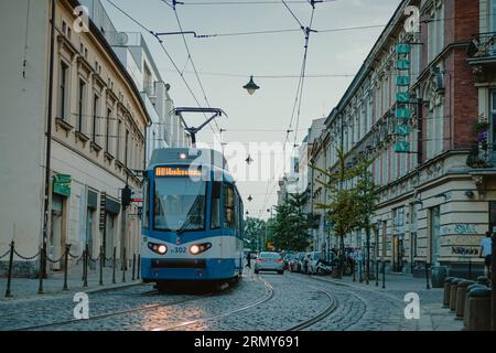 Tram pubblico blu nella città di Cracovia, in Polonia, la sera di inizio estate, pedalando per le strade della città trafficata. Tram moderno nella città polacca. Foto Stock