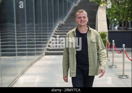 Joyful caucasian Guy passa davanti a un edificio commerciale. Foto Stock