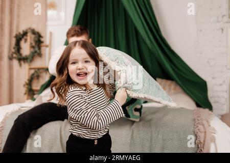 Scontri con i cuscini, giochiamo con un giovane padre felice e una figlia bambina, divertendosi a ridere per i giochi divertenti, scherzando e legando insieme a casa. Papà e gioco emozionati Foto Stock