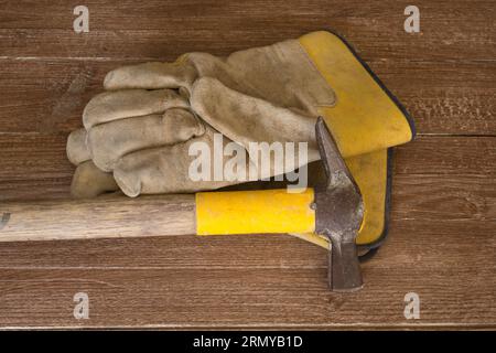 Immagine di un martello muratore e di un paio di guanti da lavoro. Riferimento al lavoro manuale e alla sicurezza sul lavoro. Foto Stock