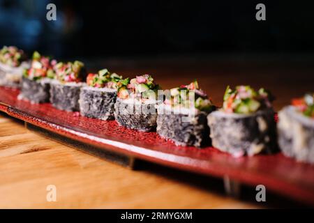Composizione primo piano di deliziosi panini serviti in un piatto rosso ceramico sul tavolo con sfondo scuro Foto Stock