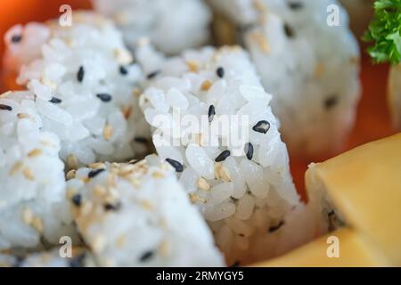 Primo piano dei tradizionali panini sushi con semi di riso e sesamo e ciuffi di prezzemolo fresco Foto Stock