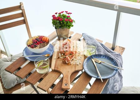 Dall'alto, frutta assortita e frutti di bosco in una ciotola posta contro bruschette e bicchieri su un tavolo di legno in terrazza Foto Stock