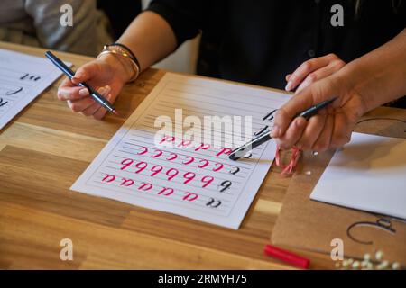Alto angolo di ritaglio insegnante irriconoscibile che punta al quaderno con lettere scritte da una studentessa anonima Foto Stock