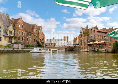 Ammira la vista da un caffè sul lungomare del centro medievale della pittoresca città di Gand, Belgio, mentre i tour in barca navigano sul fiume Leie. Foto Stock