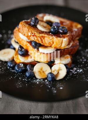 Immagine ravvicinata di un waffle dorato condito con mirtilli freschi e banane a fette Foto Stock