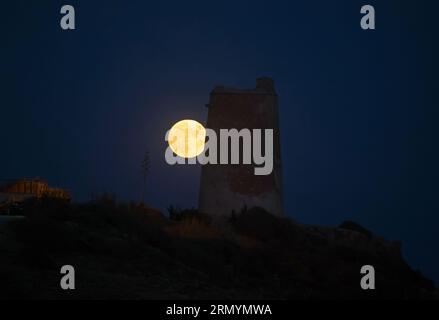 La superluna blu, la seconda superluna di agosto, sorge sul cielo accanto a una torre di pietra (conosciuta come "Torre Las Palomas") presso la spiaggia di "la Araña". La superluna blu si svolge come uno degli eventi astronomici più suggestivi del mese. Quando la luna piena ha luogo, appare più grande e più luminosa del normale. Foto Stock