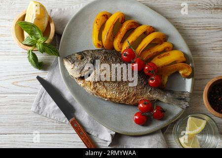 Delizioso pesce dorado arrosto servito con verdure su un tavolo di legno, piatto Foto Stock