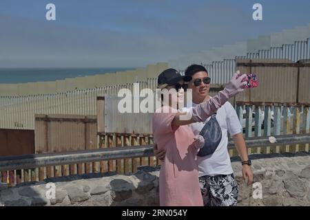 Tijuana, Baja California, Messico. 30 agosto 2023. I turisti posano per un selfie vicino alla costruzione che continua sul confine della spiaggia di Playas de Tijuana che divide San Diego e Baja California, Messico. Lo smantellamento della recinzione primaria è avanzato quando i lavoratori hanno scavato un buco di 20 piedi per installare pannelli di parete di 30 piedi che passeranno attraverso il centro di Friendship Park e lungo la spiaggia che entra nell'Oceano Pacifico mercoledì 30 agosto 2023. (Immagine di credito: © Carlos A. Moreno/ZUMA Press Wire) SOLO USO EDITORIALE! Non per USO commerciale! Foto Stock