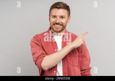 Soddisfatto uomo di mezza età sorridente punta ampiamente con indice nell'angolo destro spazio vuoto per l'annuncio. Foto Stock
